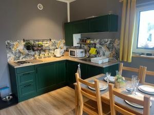 a kitchen with green cabinets and a table with chairs at Domki z Widokiem in Radków