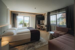 a bedroom with a bed and a couch and a window at Hotel am Hopfensee in Füssen +74 photos