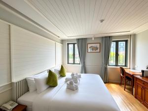 a large white bed in a room with a desk at TUAN Hotel Bangkok near Wat Arun in Bangkok Yai