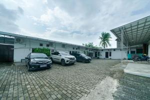 three cars parked in a parking lot in front of a building at JM Guest House Lamaran RedPartner in Karawang