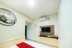 a room with a tv on the wall and a red rug at JM Guest House Lamaran RedPartner in Karawang