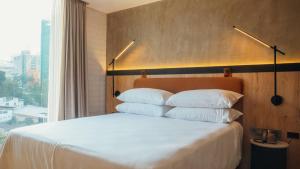 a bed with white pillows in a room with a window at Faranda Collection Medellin, a Member of Radisson Individuals in Medellín +54 photos