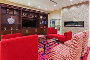 a living room with red chairs and a flat screen tv at Clarion Hotel The Colony - Plano West in The Colony