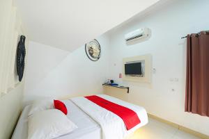 a white room with a bed and a clock on the wall at JM Guest House Lamaran RedPartner in Karawang