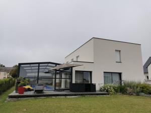 a white house with a patio and an umbrella at La Belle Vue Piscine chauffée et abritée, vue sur l'océan, plage à pied, bord de mer, BRETAGNE LBC in Clohars-Carnoët