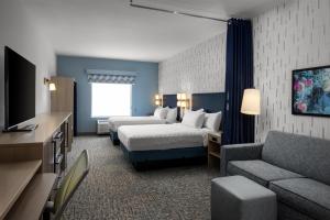 a hotel room with two beds and a couch at Home2 Suites By Hilton Salisbury Fruitland in Fruitland