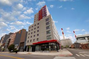 a tall white building with a red at Hampton Inn Long Island City NY in Long Island City