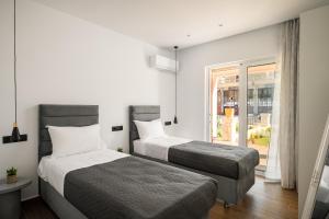 two beds in a hotel room with a window at Lumino Suites Corfu in Corfu