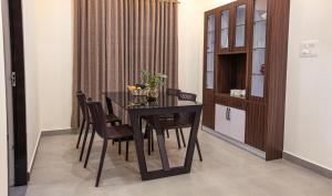 a dining room with a black table and chairs at Feliz Homes Kottakkal in Kottakkal