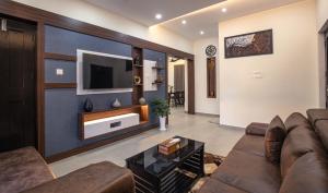 a living room with a couch and a tv on a wall at Feliz Homes Kottakkal in Kottakkal