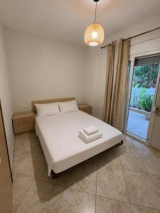 a bedroom with a white bed and a window at Val beach apartment in Nea Potidaea