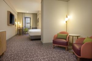 a hotel room with a bed and two chairs at Hilton Edinburgh Carlton in Edinburgh