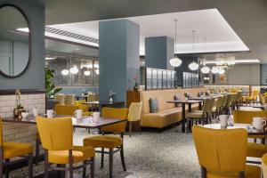 a dining room with tables and yellow chairs at Hilton Edinburgh Carlton in Edinburgh