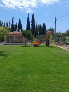 a playground with a slide in a green yard at Marathon Beachside Villa 100m from the beach in Schinias