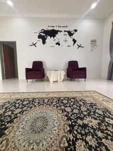 a room with two chairs and a map of the world at Damai Ria INAP DESA in Jerantut