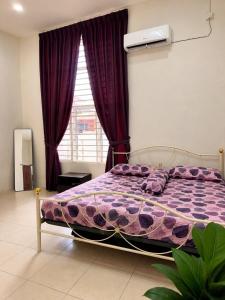 a bedroom with a purple bed and a window at Damai Ria INAP DESA in Jerantut