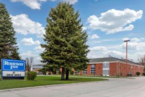 a sign next to a pine tree in front of a building at Rodeway Inn Columbia Mall Loop in Grand Forks