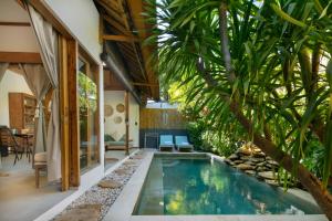 an indoor pool with a palm tree in a house at Villa Casa Koko in Gili Islands