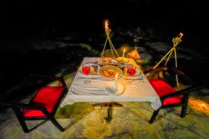 a dinner table with two red chairs and candles at Taro River Resort Negombo in Otarawadiya
