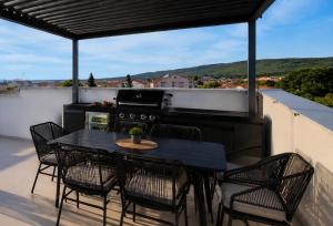 a patio with a black table and chairs and a stove at Sunset Aura in Sukošan