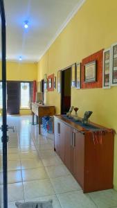 a room with yellow walls and a table and a piano at D'Oen House Banjarbaru in Banjarbaru