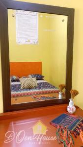 a mirror reflecting a bed in a room at D'Oen House Banjarbaru in Banjarbaru