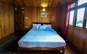 a bedroom with a bed with wooden walls and windows at Pine Haven Resorts in Takdāh +39 photos