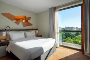 a bedroom with a bed and a large window at DoubleTree by Hilton Paris Boulogne in Boulogne-Billancourt +77 photos