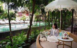 a woman sitting in a chair next to a pool at Serenity Boutique in Siem Reap