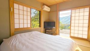 a bedroom with a bed and a tv and windows at 伊根の宿 汐風 Shiokaze in Nomuro