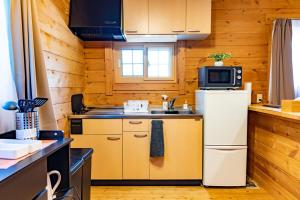 a small kitchen with a refrigerator and a microwave at Mtd大分天ヶ瀬 in Hita