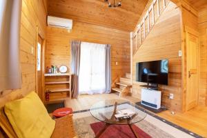 a living room with a tv and a glass table at Mtd大分天ヶ瀬 in Hita