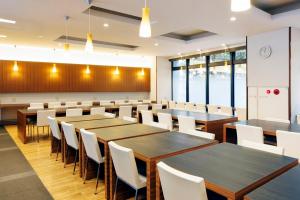 a conference room with wooden tables and white chairs at JR Inn Sapporo in Sapporo