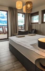 a bedroom with a large bed with two tables and windows at Pensjonat Kotwica in Kuźnica