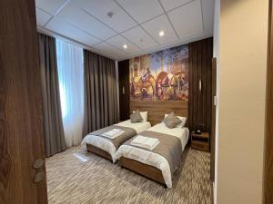 a bedroom with two beds and a painting on the wall at Imam Bukhari Grand Hotel in Khodzha-Ismail +5 photos