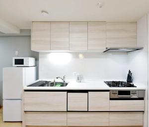 a kitchen with wooden cabinets and a white refrigerator at Room 501 Japanese Tatami 3LDK 75sqm Near Namba Family Friendly Stay in Osaka
