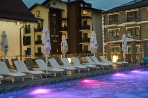 a row of chairs and umbrellas next to a swimming pool at Goral Hotel & Spa in Bukovel