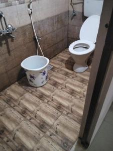 a bathroom with a toilet and a bucket on a wooden floor at Royal Residency in Gingee