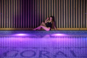 a woman sitting on the edge of a swimming pool at Goral Hotel & Spa in Bukovel