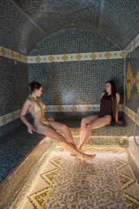two women sitting in a bathroom with their legs on a surfboard at Goral Hotel & Spa in Bukovel