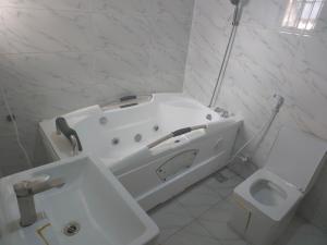 a white bathroom with a tub and a toilet at House 27 Alpha in Idu