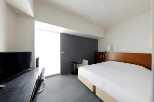 a bedroom with a bed and a flat screen tv at JR Inn Sapporo in Sapporo +27 photos