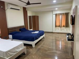 a bedroom with two beds and a ceiling fan at SSR PARADISE ROOMs in Kavarapettai