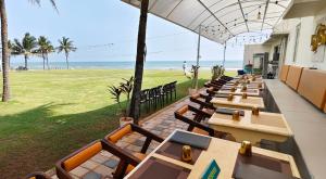 a row of tables and chairs with the beach in the background at Shelter Beach Resort in Mahabalipuram