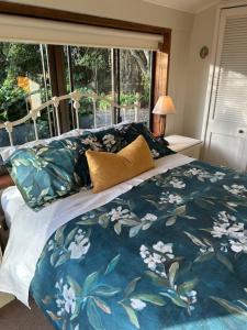 a bed with a blue and white comforter and a window at McIvor Lodge in Invercargill