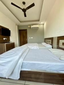 a bedroom with a large white bed with a ceiling fan at Laksh hotel,Proprietor Dilbag in Kurukshetra +3 photos