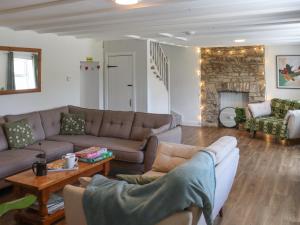 a living room with couches and a stone fireplace at Pantglas in Llandysul