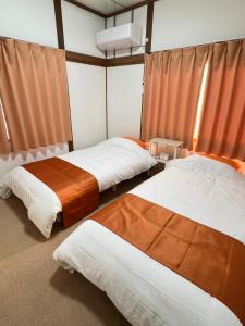 two beds in a room with orange curtains at 民泊びんご1 in Onomichi +8 photos