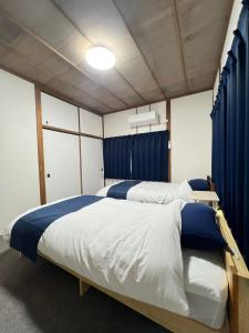 two beds in a room with blue curtains at 民泊びんご1 in Onomichi