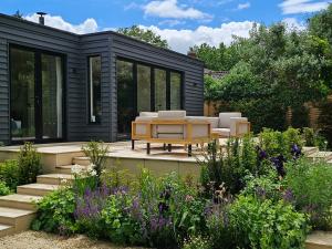 a black house with a bench and a table in a garden at Fairview in Saxmundham